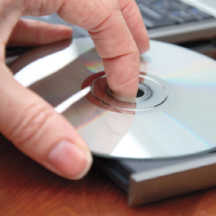 hand places CD into computer drive
