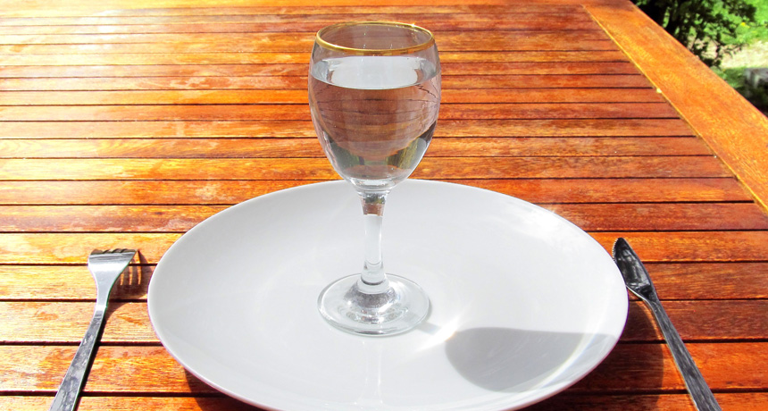 glass of water on an empty plate