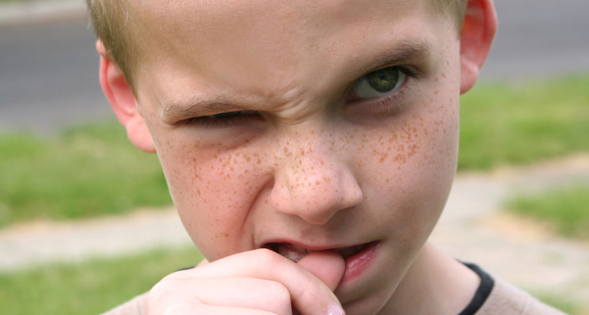 young boy biting his fingernails