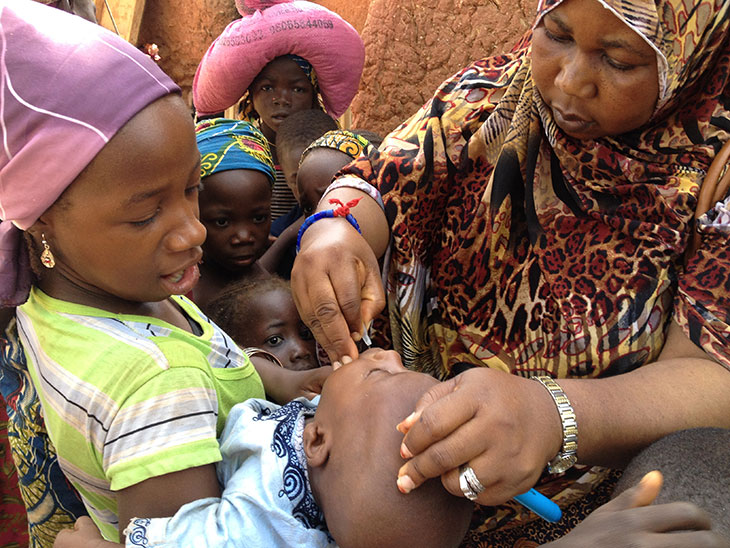 woman giving baby polio vaccine in Nigeria