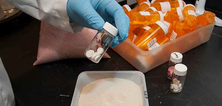 person holding container with pills