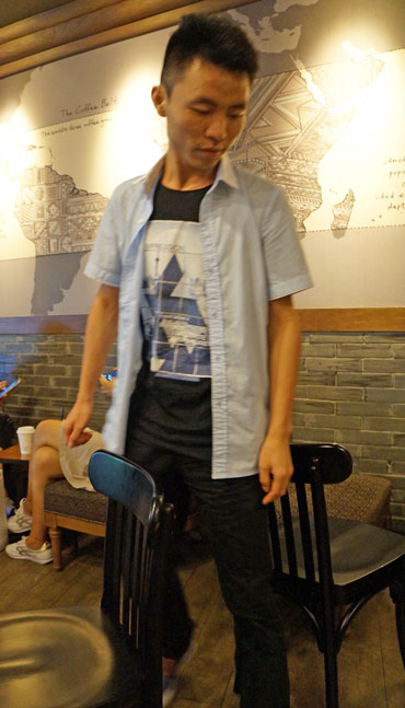 man squeezing through chairs