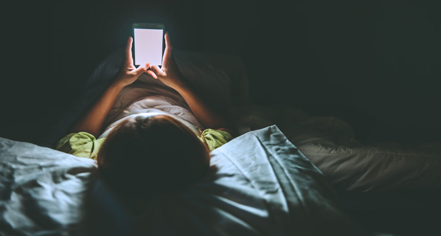 person lying in bed and a smartphone
