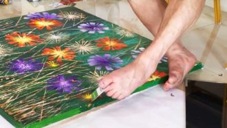 person painting with paintbrush held in their toes
