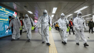 people in clean suits spraying a subway tunnel