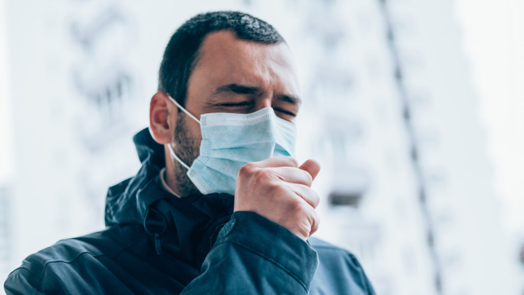 man wearing a mask and coughing