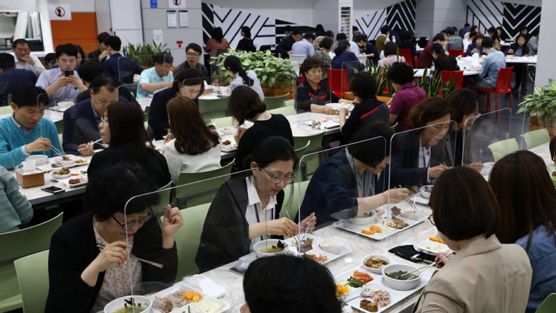 People eating at a restaurant with plexiglass barriers