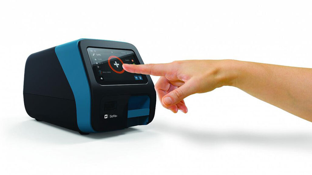 A finger pointing at the screen of a black and blue medical device