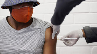 Person getting a vaccine shot in their left arm
