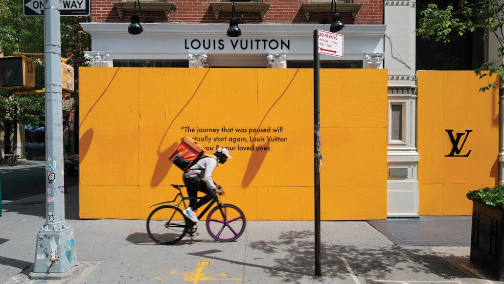 bike messenger in front of a boarded up Louis Vuitton store
