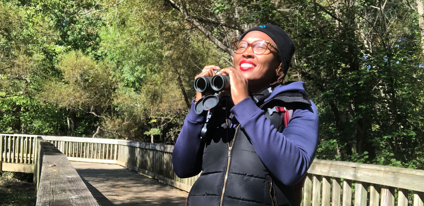 Deja Perkins standing in a park and holding a pair of binoculars
