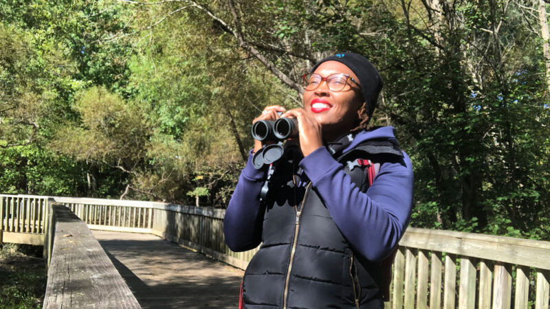 Deja Perkins standing in a park and holding a pair of binoculars