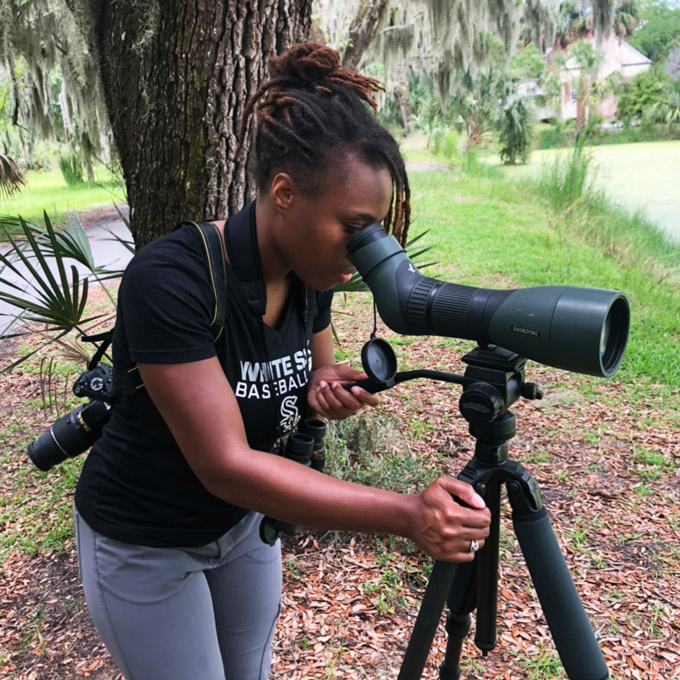 Deja Perkins birding and looking through a telescope on a tripode