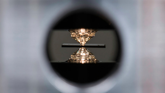 a material being squeezed between the tips of two diamonds