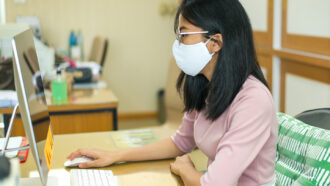 masked student looking at a computer