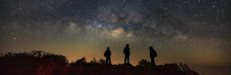 Three people looking at night sky. Einstein's general relativity changed how we understand our universe.