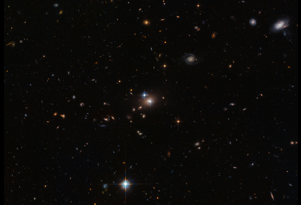 starry image with bright spot at center. This image shows a single quasar that looks like two thanks to gravitational lensing.