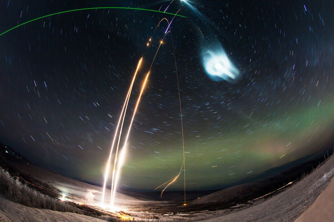 time-lapse photo of three rocket launches and chemical tracers in night sky