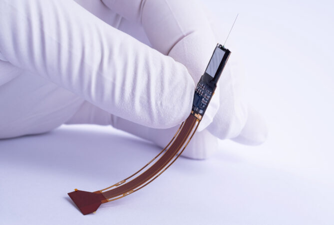 a gloved hand holds a roughly two-inch long device