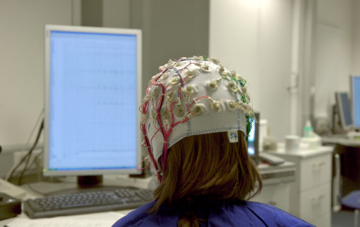 a person seen from behind wearing a white EEG cap