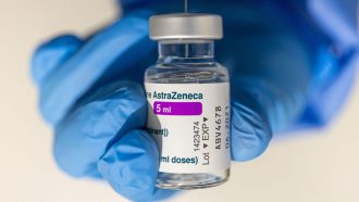 hands holding a vial of AstraZeneca's covid-19 vaccine