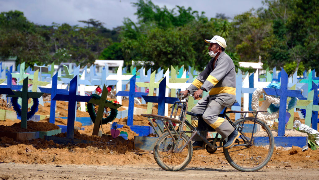 man riding a bicycle in front of cemetery graves in Manaus, Brazil