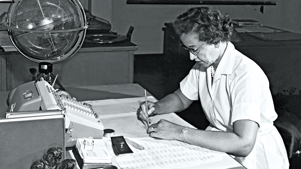 black and white photo of Katherine Johnson sitting at a desk