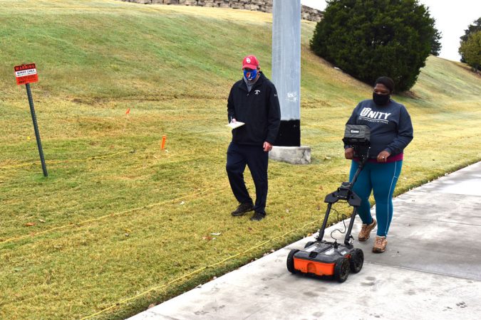 Scott Hammerstedt looks on while Alicia Odewale pushes a ground survey machine