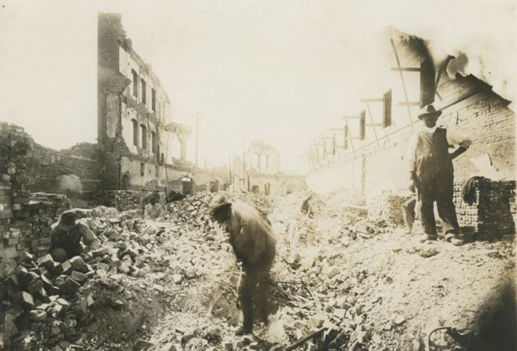 Three men salvage bricks from the ruins of the Gurley Hotel