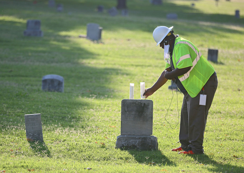 Kavin Ross places candles on Eddie Lockard's headstone