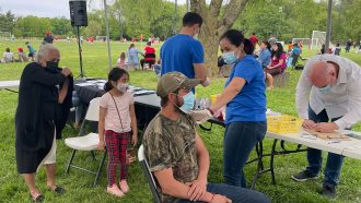 Melissa Pluguez gives a man the COVID-19 vaccine at an outdoor outreach event