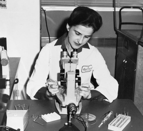 black and white image of Beatrice Mintz looking into a microscope