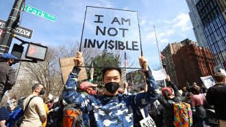 protester holds a sign that reads "I am not invisible"