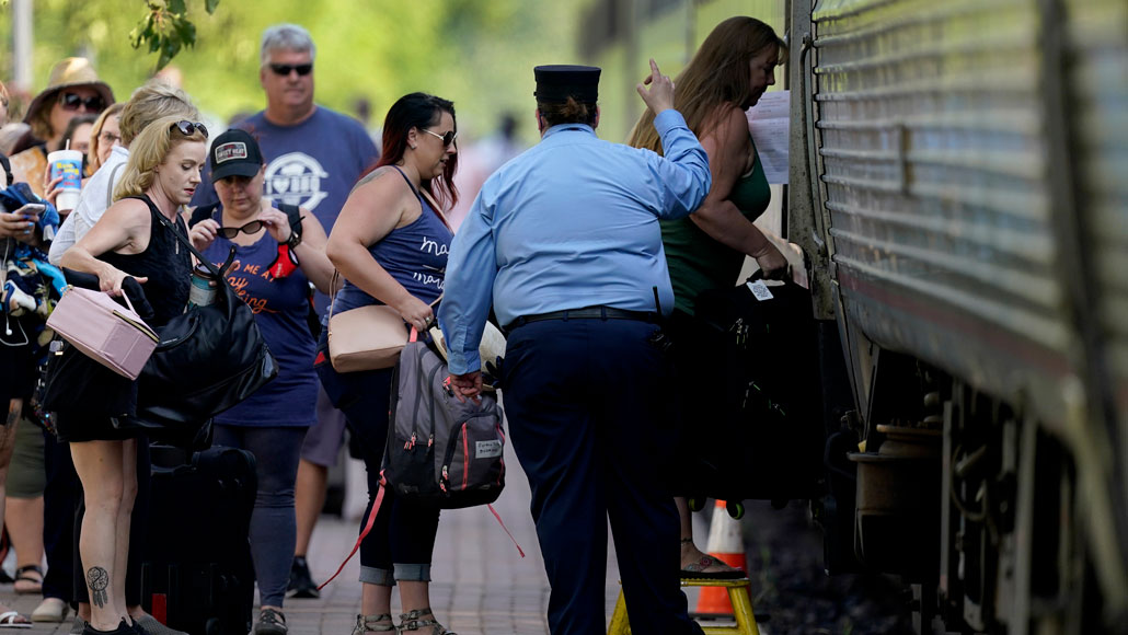 a train conductor monitors people boarding a train car