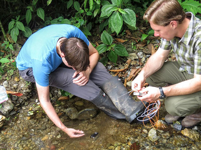 Chris and James Boccia handling a lizard in a stream habitat
