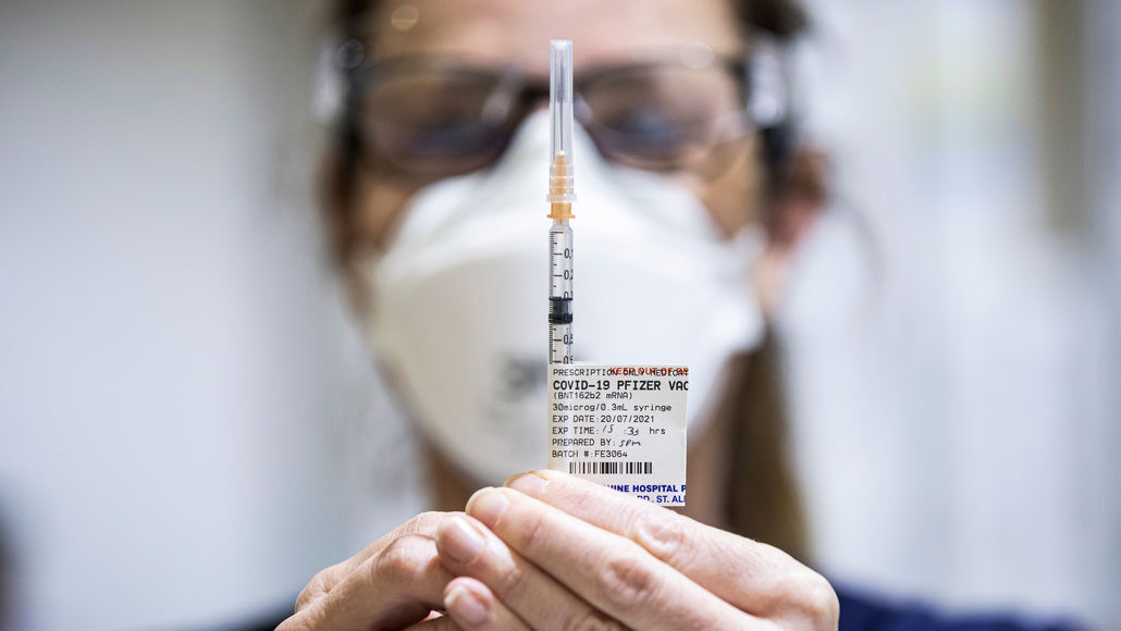 a person prepares a syringe with a Pfizer COVID-19 vaccine dose