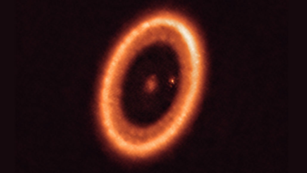star PDS 70 surrounded by dusty ring of debris, with bright dot inside ring that may be a moon forming