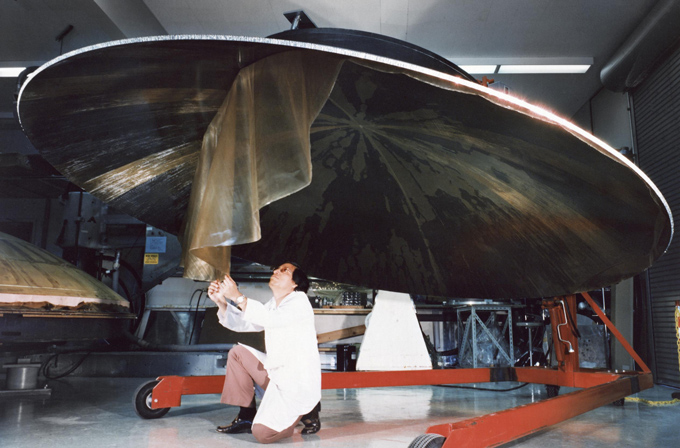 a person crouched down under a dish-shaped antenna