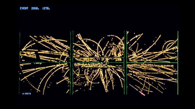 an computer illustration of streaks of yellow bouncing around in loops - showing how the debris from a proton-antiproton collision moved. the straighter path of a high-energy electron is also shown