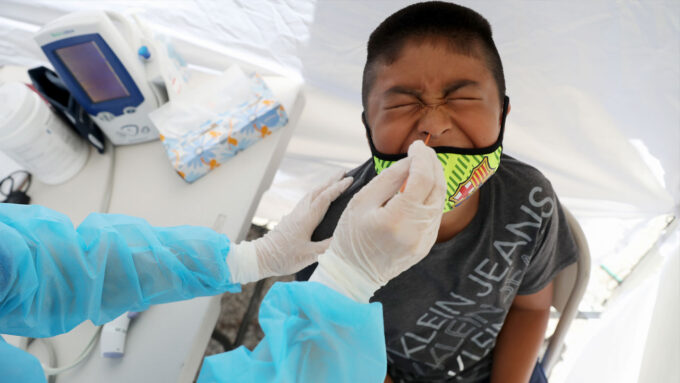 a child grimaces while his nose is swabbed