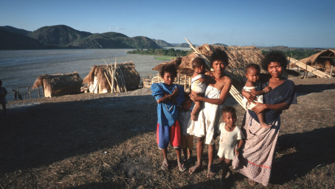 a group of Ayta people in front of huts beside a river