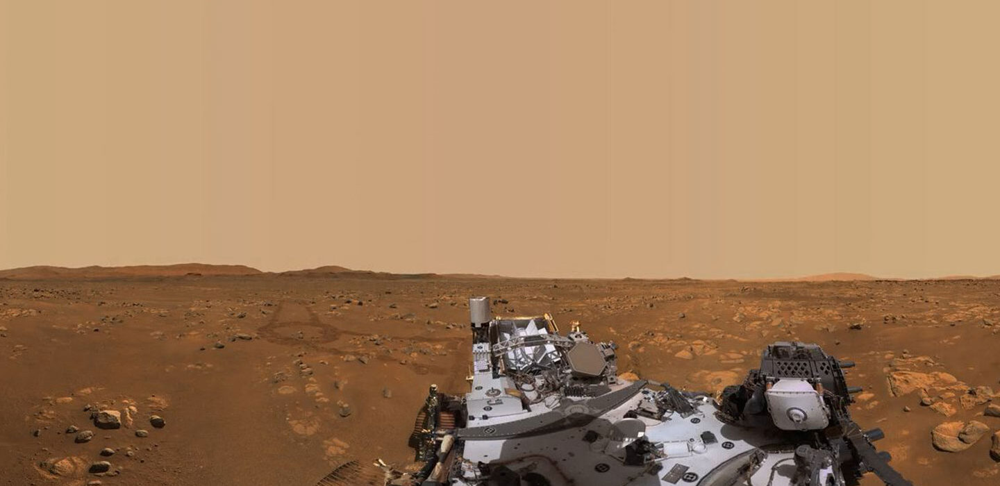 A photo of the Martian landscape with part of the Perseverance rover in the foreground
