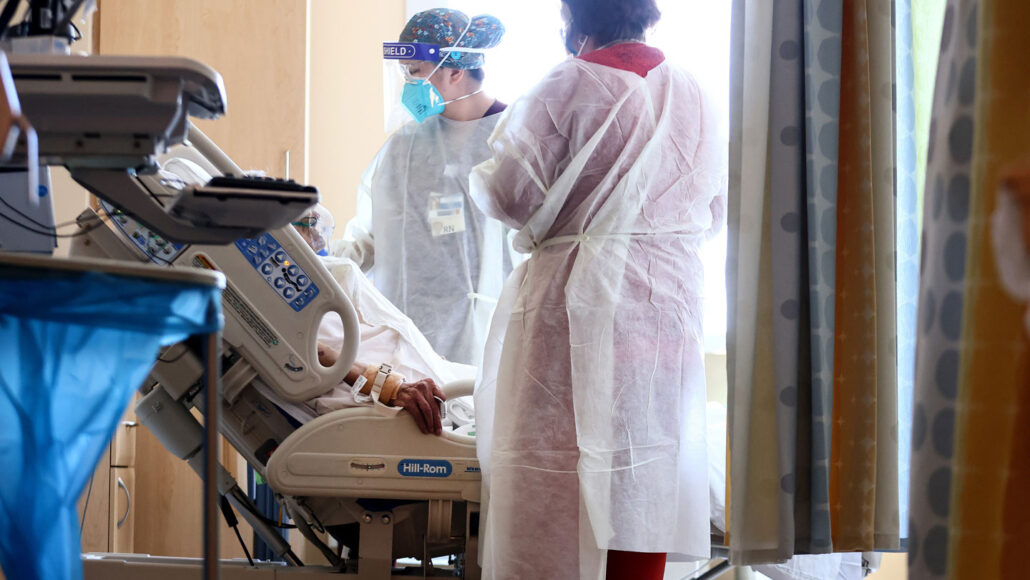 doctors tend to a COVID-19 patient in a hospital bed