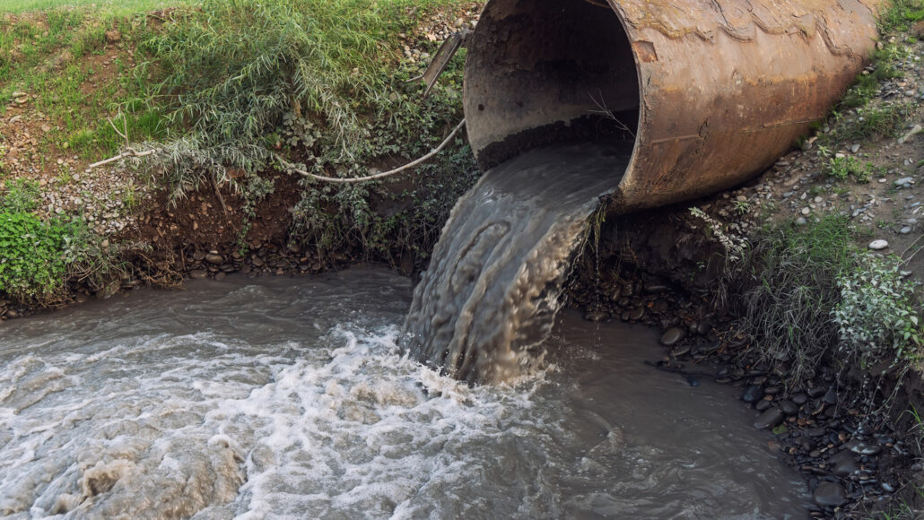 sewage runoff pours out of a drainpipe