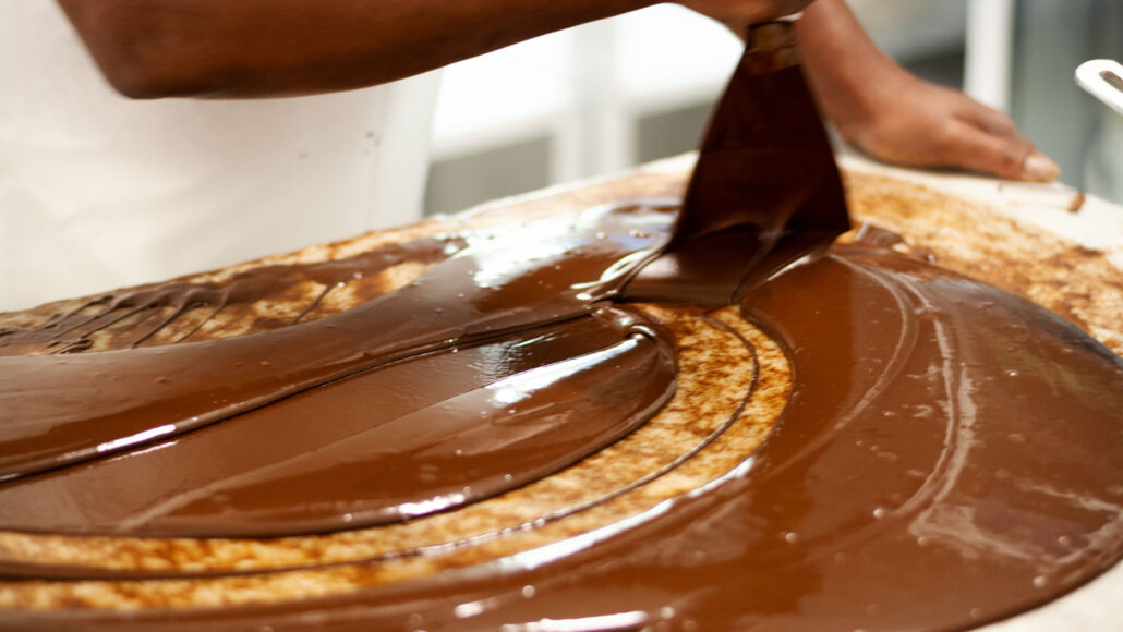 tempered chocolate being spread over a pastry