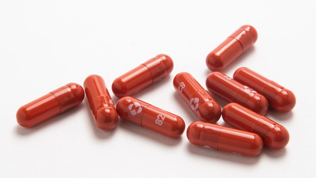 ten reddish molnupiravir pills on a white background