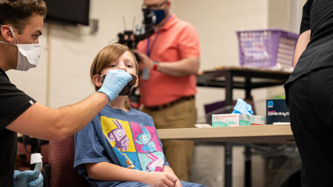 Elementary school student receiving a COVID-19 test from a person wearing a mask and gloves