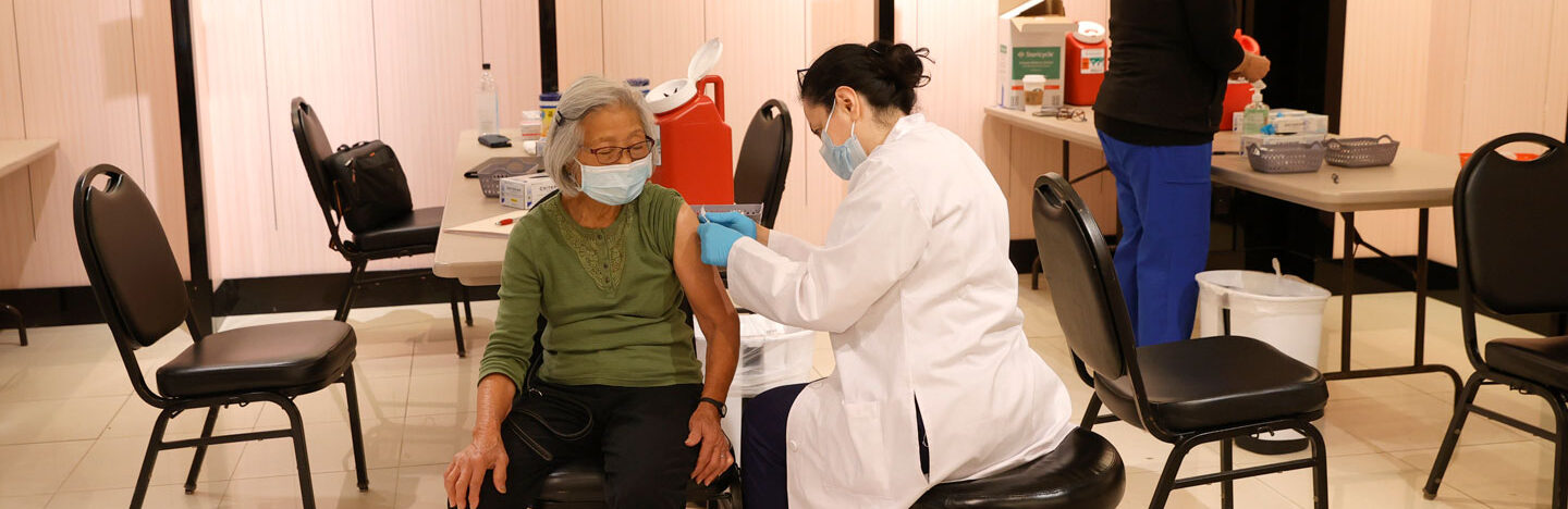 woman receiving a booster shot from a pharmacist