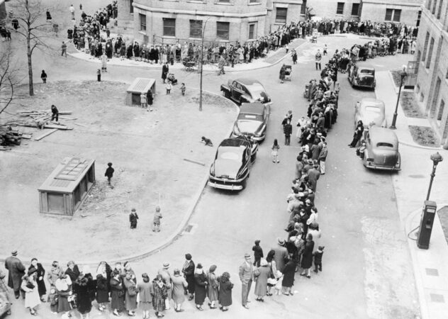 black and white photo taken from above of a long line of people snaked out into the street