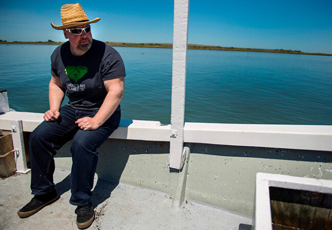 marine biologist David Schulte wearing a hat and sunglasses, sitting offshore